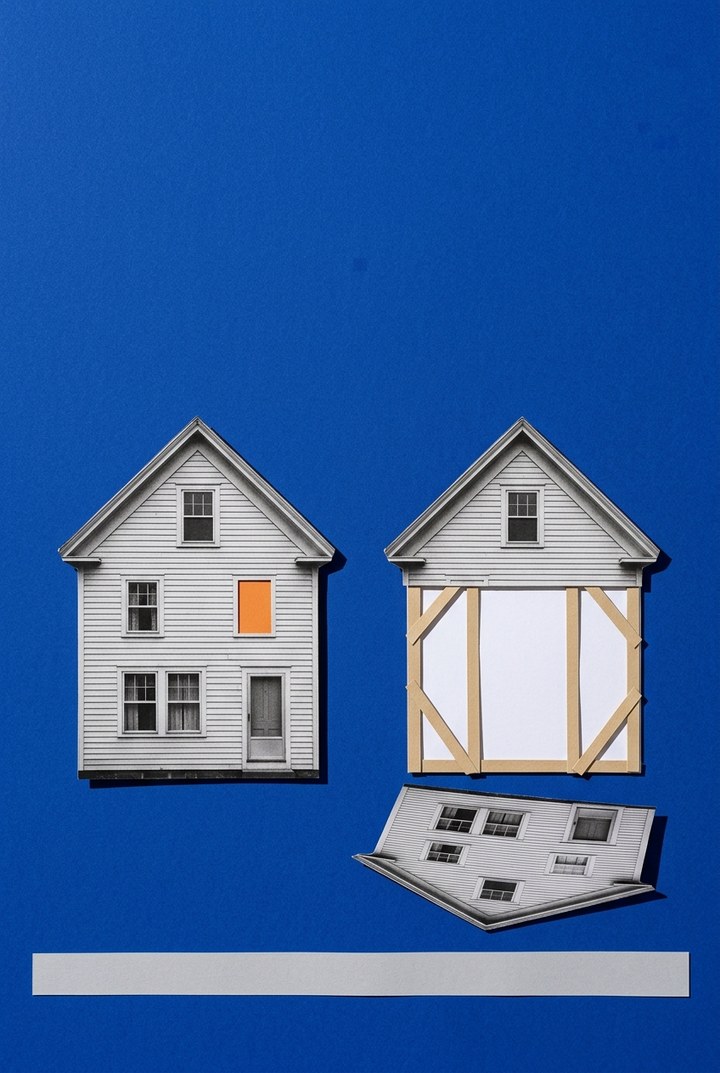 A cut-paper collage on a deep blue field: two identical clapboard houses side by side, the left one whole with a single orange window, the right one reduced to a hollow set of kraft-paper braces around a blank white rectangle, its fallen facade lying cut-out at the base beside a strip of gray street.
